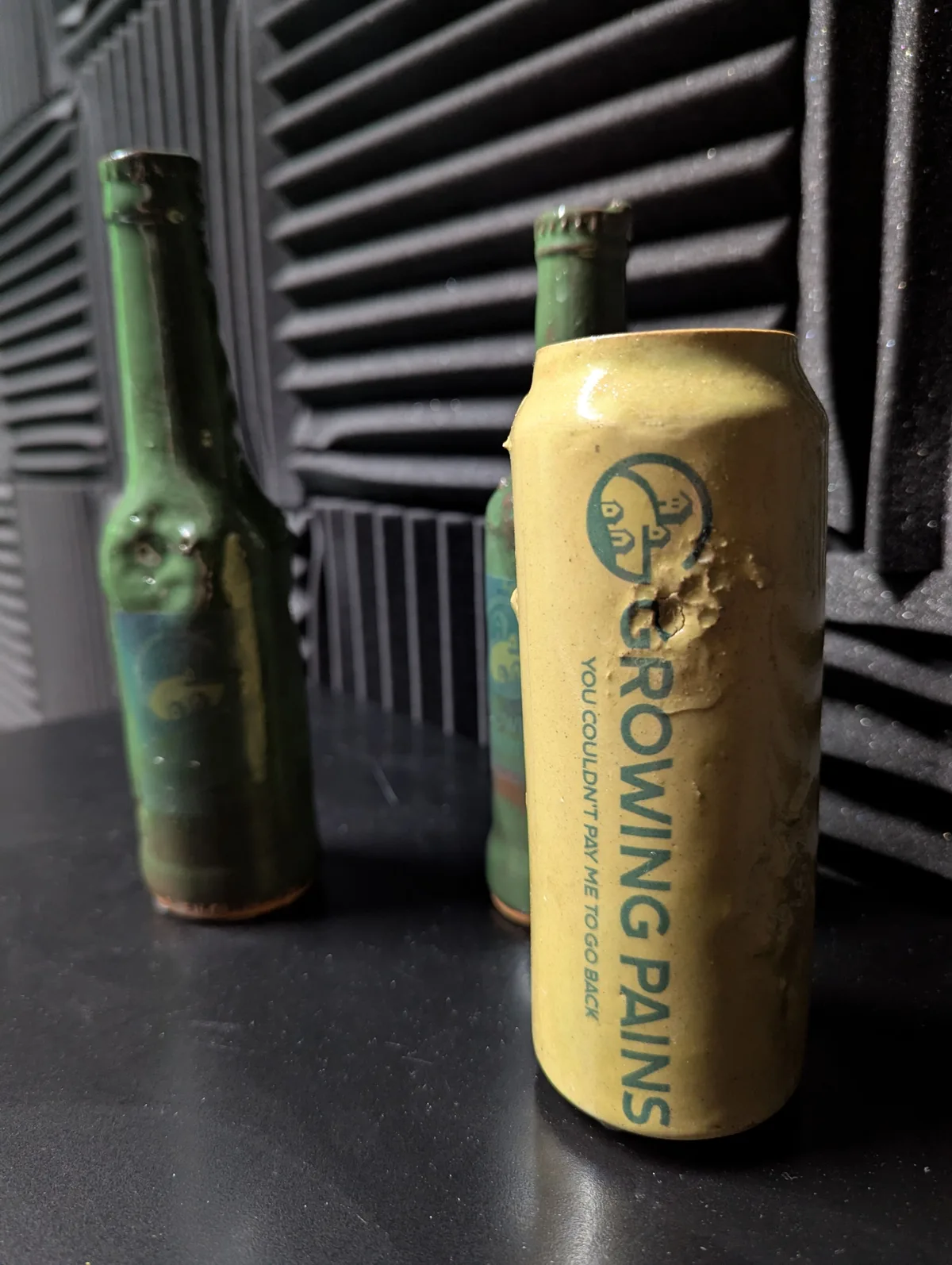 Handmade ceramic bottles and a can, glazed and stamped with the Growing Pains logo