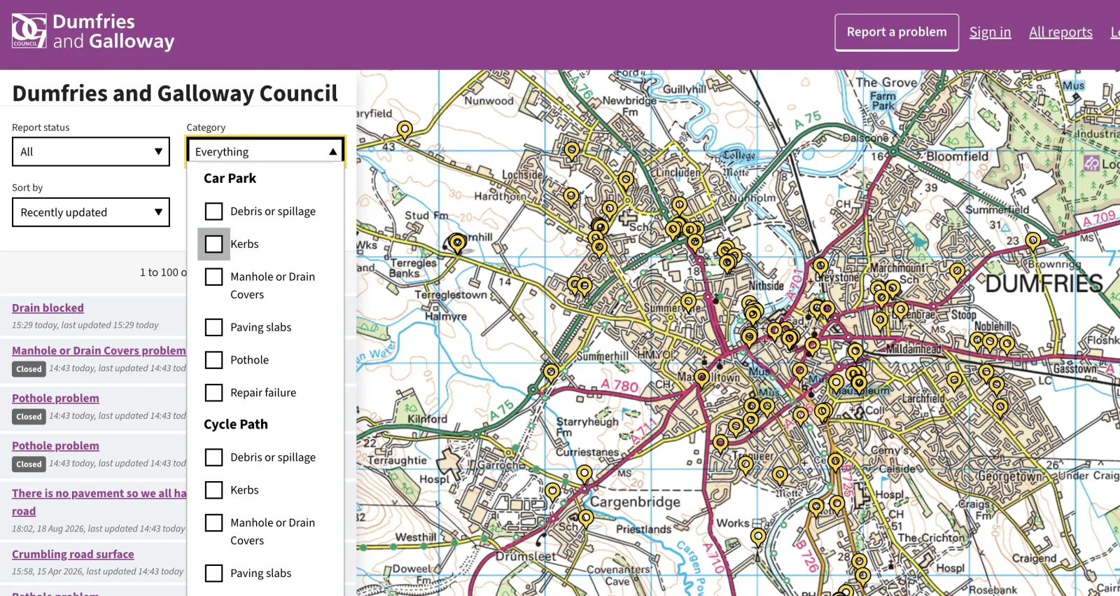 The council's FixMyStreet reports map of Dumfries with the category menu open, listing problem types such as kerbs, manhole or drain covers, paving slabs, potholes and repair failures
