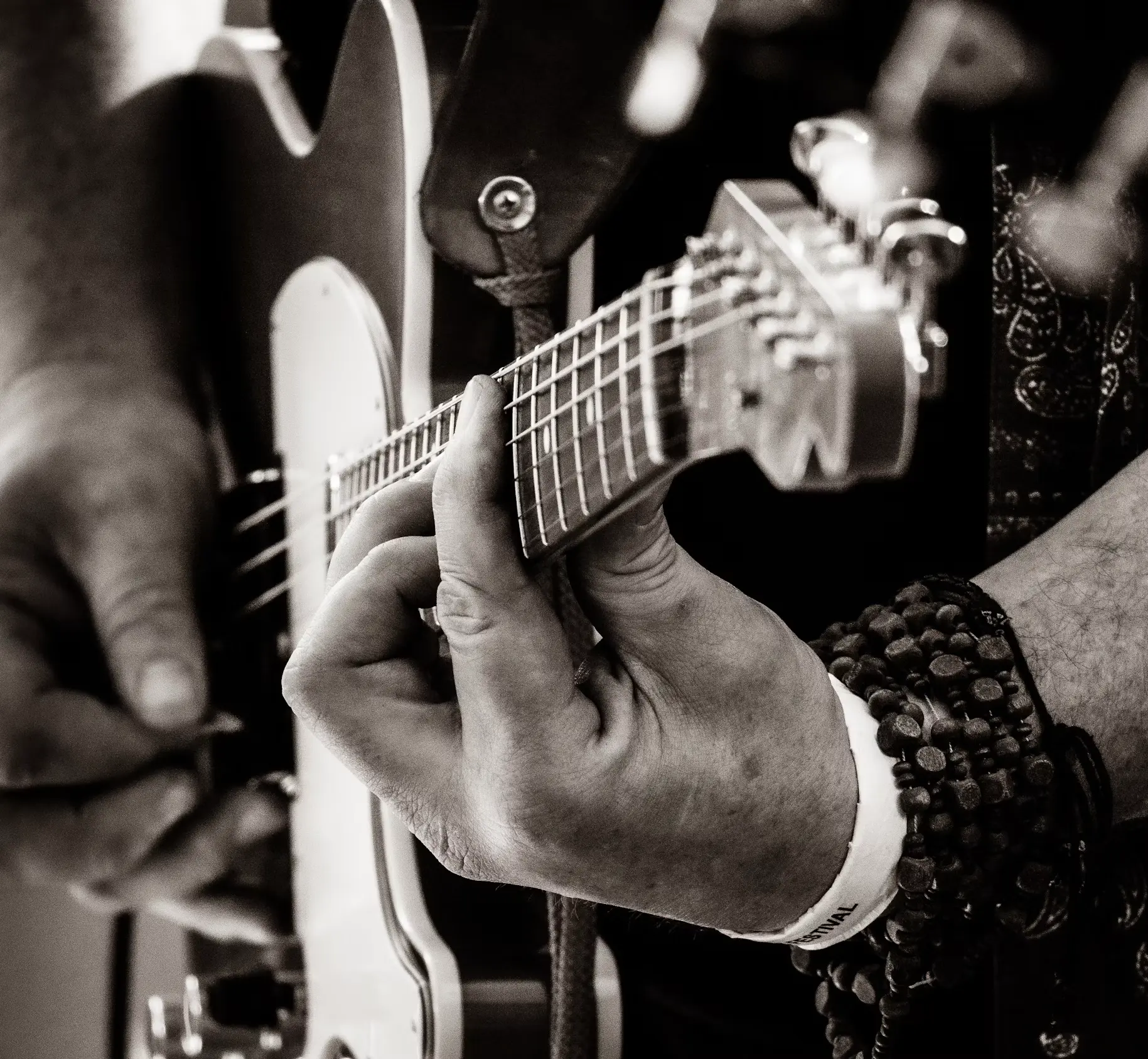 Shine on you diamonds Close-up of a guitarist's hands on the fretboard, a festival wristband on one wrist
